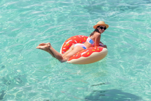 Preview: Beautiful woman with inflatable donut in sea