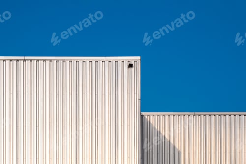 Preview: Two Corrugated iron Industrial Warehouse Buildings against blue clear sky Background