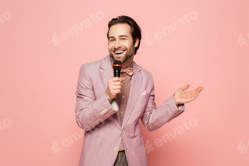 Preview: Positive host of event talking at microphone isolated on pink