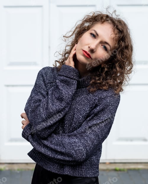 Preview: Serene woman posing in front of white wall.