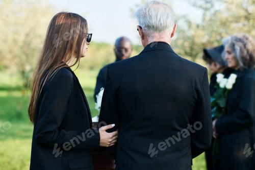Preview: Back view of young woman in black attire supporting mature man with white hair