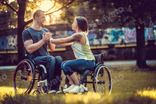 Preview: Handicapped young couple on two wheelchairs kissing .