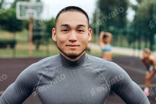 Preview: Portrait of handsome, smiling Asian man wearing sportwear looking at camera, posing outdoors