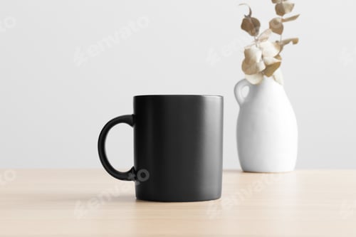 Preview: Black mug mockup with an eucalyptus decoration on the wooden table.