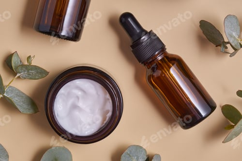 Preview: anti-aging collagen facial serum in dark glass bottle and face cream on beige background with eucaly