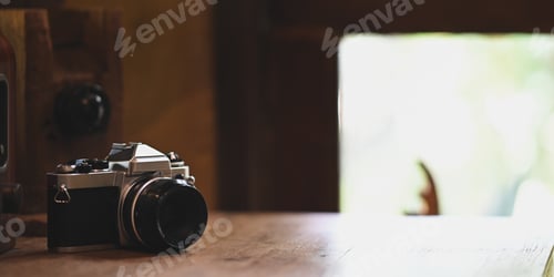 Preview: Retro camera putting on wooden table over vintage wooden room as background.