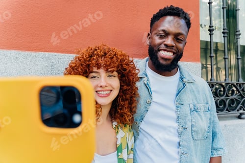 Preview: A multiracial couple takes a selfie sharing a playful moment in an urban setting.