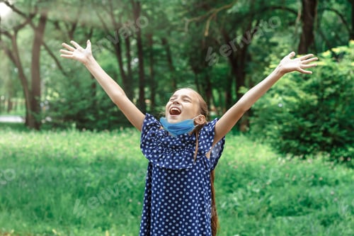 Preview: Quarantine is over concept. Little girl taking off mask outdoor and smiles.