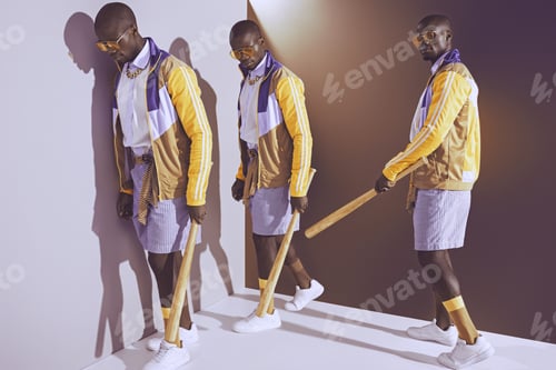 Preview: Sequence shot of stylish young african american man with baseball bat walking in studio
