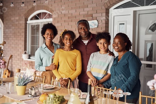 Preview: Happy African American extended family gathering for meal on a patio and looking at camera.