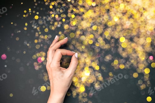 Preview: Woman hand with golden bokeh lights on background
