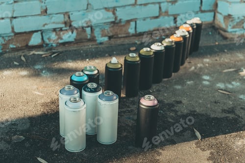 Preview: cans with aerosol paint standing in row on asphalt