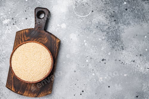 Preview: White sesame seeds in a wooden bowl. grey background. top view