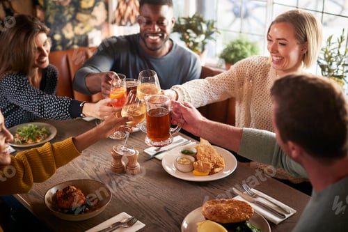 Preview: Friends Meeting For Meal In Traditional English Pub Making Toast Together