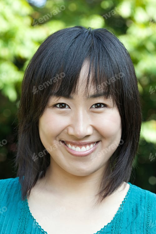 Preview: Portrait of a smiling woman with a green top against a natural backdrop.