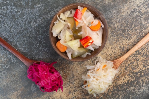 Preview: Two spoons of cabbage with wooden bowl of salty vegetables
