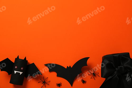 Preview: Gift box and paper bat on orange background, space for text