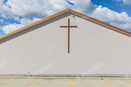 Preview: A large cross on the exterior wall of a church in a small town.