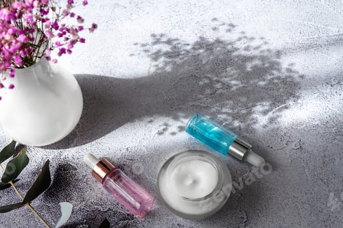 Preview: Cosmetics serum and cream on a marble white background with a bouquet of pink flowers, shadows