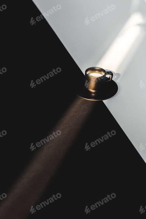 Preview: high angle view of cup of milk in black cup on black and white surface