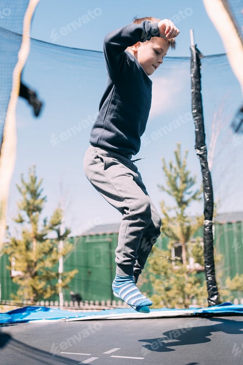Preview: Little boy jumping in trampoline in the park. Children's leisure outdoors, lifestyle concept
