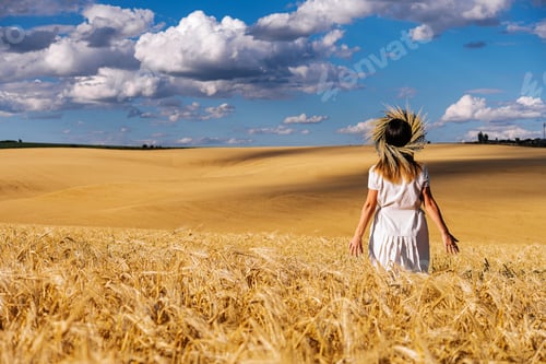 Preview: Woman in white dress stands in field with wheat