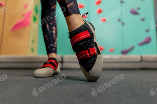 Preview: close-up of girl's legs on a climbing wall wearing professional climbing shoes