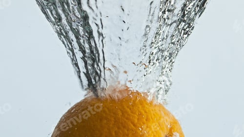 Preview: Fresh orange splashing water in light background closeup. Tropical fruit bounce