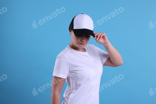 Preview: Woman in white t-shirt and baseball cap on light blue background. Mockup for design
