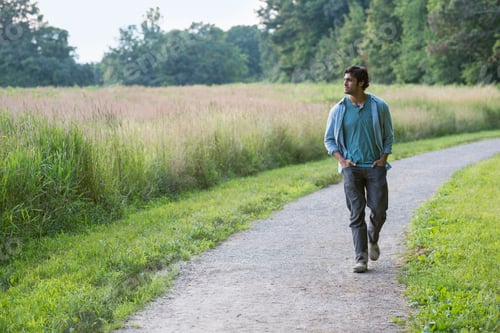 Preview: A young man walking down a path with his hands in his pockets.