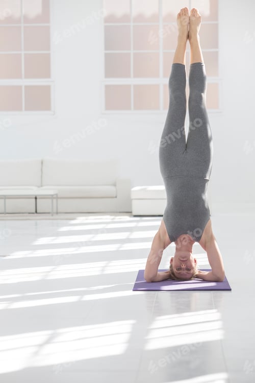 Preview: Woman practicing headstand yoga pose in a bright, airy room