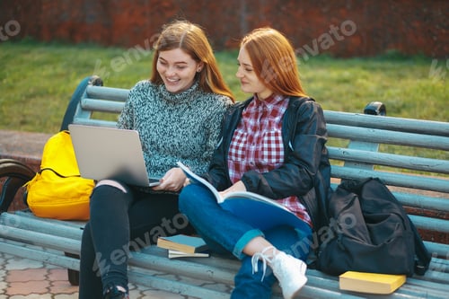 Preview: Two Young Women Study Together on a Park Bench