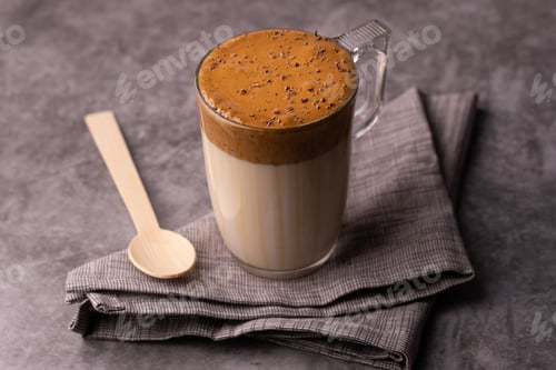 Preview: Closeup of a glass of creamy dalgona coffee sprinkled with chocolate with napkin and wooden spoon