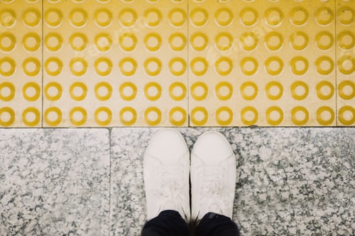 Preview: top view of woman feet at train station,yellow floor with relief to indicate the end of the platform