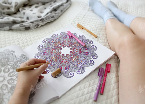 Preview: Woman's legs, relaxing in bed on the weekend with pens and a coloring book
