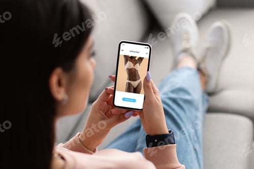 Preview: Young arab woman use phone for online shopping, choose underwear in fashion store on screen, rest