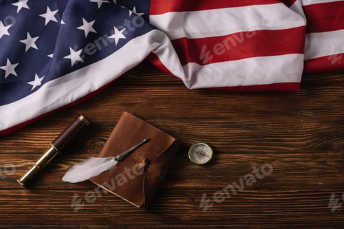 Preview: top view of leather notebook, telescope, nib and compass on wooden surface with American national