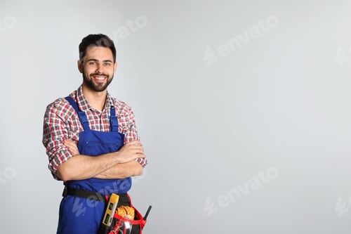 Preview: Portrait of construction worker with tool belt on light background. Space for text