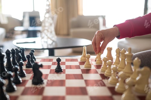 Preview: Woman playing chess game making a strategic move in living room