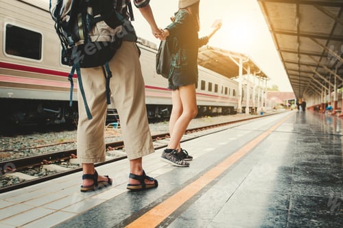 Preview: Man and woman holding hands at train station.