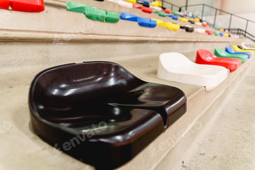 Preview: Close-up of a black plastic seat in the stands of a sports center, empty.