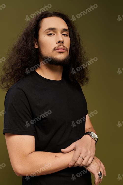 Preview: Handsome young man with a beard poses confidently against a solid backdrop