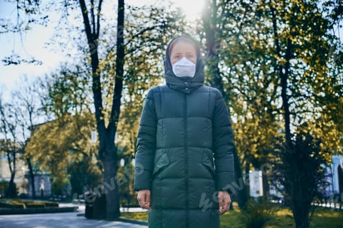 Preview: Young woman on empty street wearing face mask during coronavirus quarantine