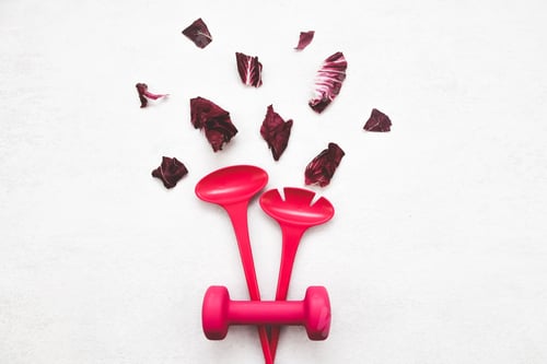 Preview: Salad spoons, a dumbbell and lettuce leaves lie in the center on a light cement .