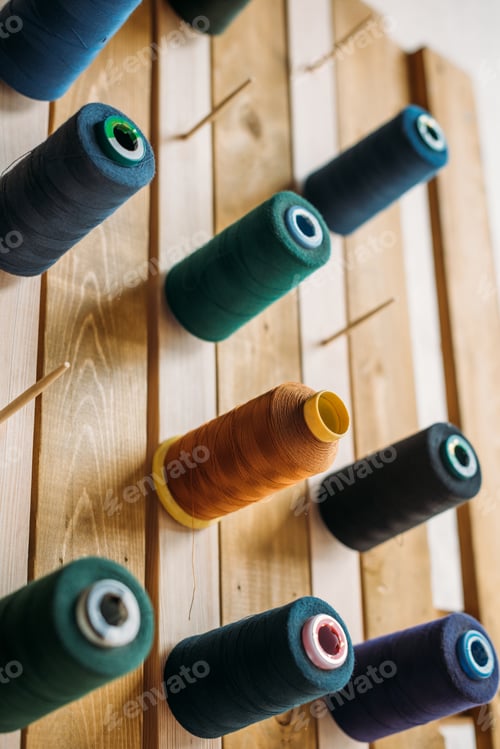 Preview: colored thread coils hanging on wooden surface at sewing workshop