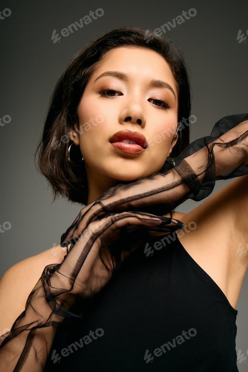 Preview: Stylish young woman poses confidently in sheer black accessories against a neutral backdrop