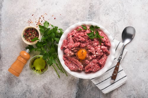 Preview: Raw minced meat. Ground meat beef, pork or lamb spices, herbs and eggs on white plate on light grey