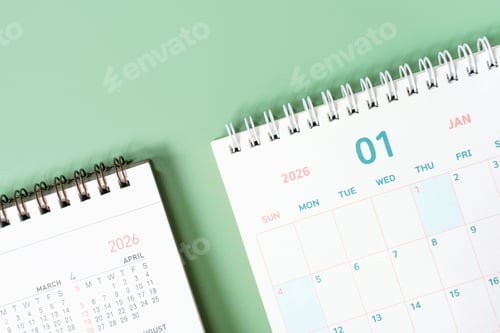 Preview: Paper calendars for 2026 on green background close-up.