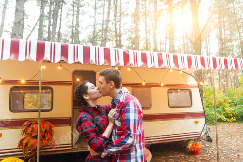 Preview: Portrait of romantic couple smiling while holding hands near house on wheels outdoors