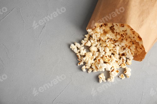 Preview: Paper bag with tasty popcorn on grey background, top view
